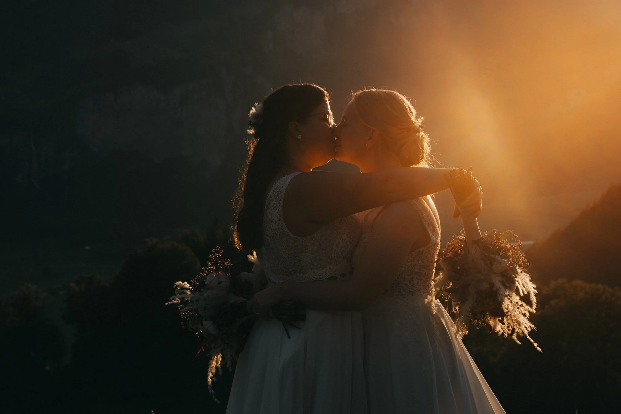 Hochzeitskuss im letzten Sonnenlicht – das queere Paar feiert ihre Liebe im Berner Oberland.
