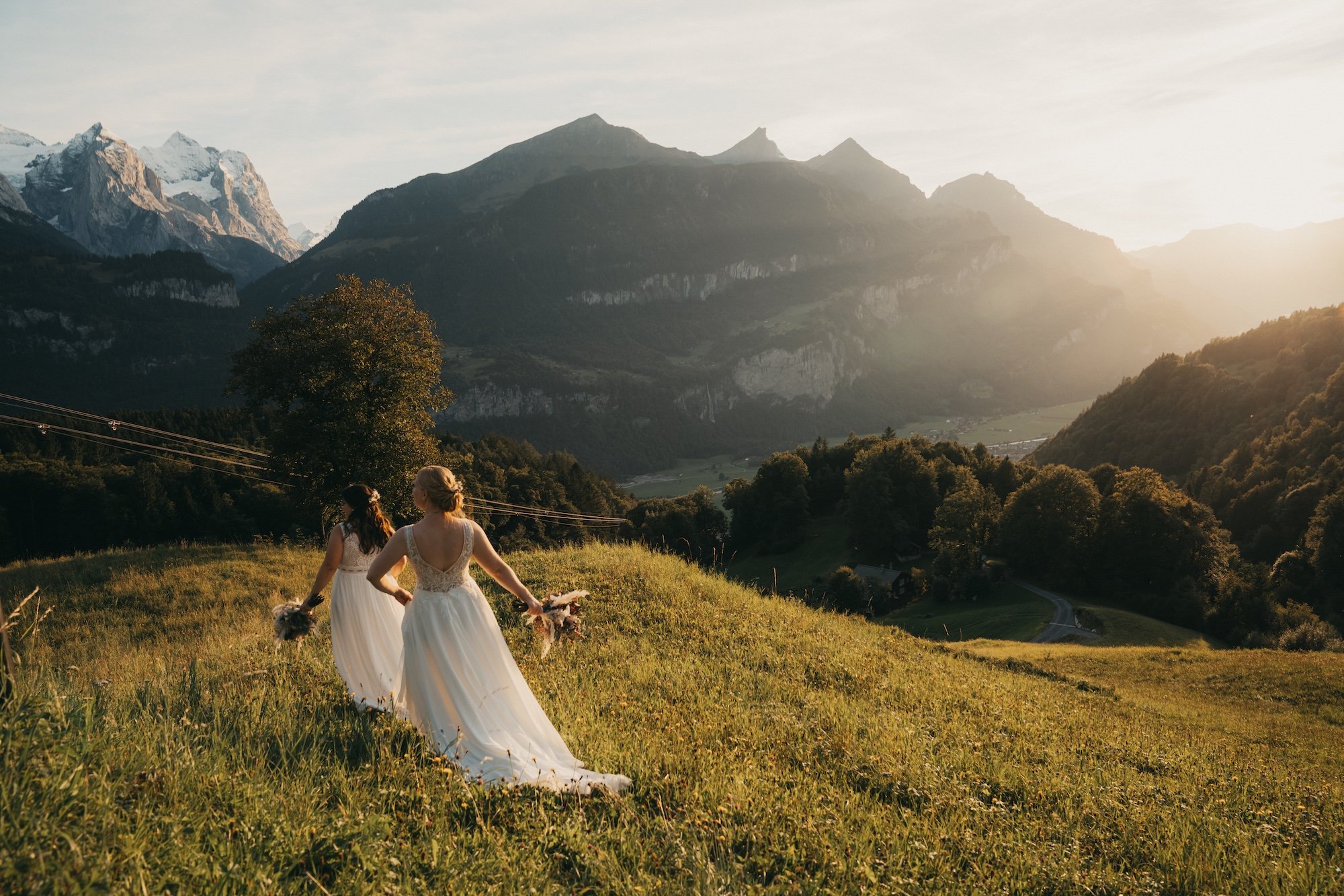 Hand in Hand durch die Bergwiese im Sonnenuntergang – Hochzeit auf dem Hasliberg.