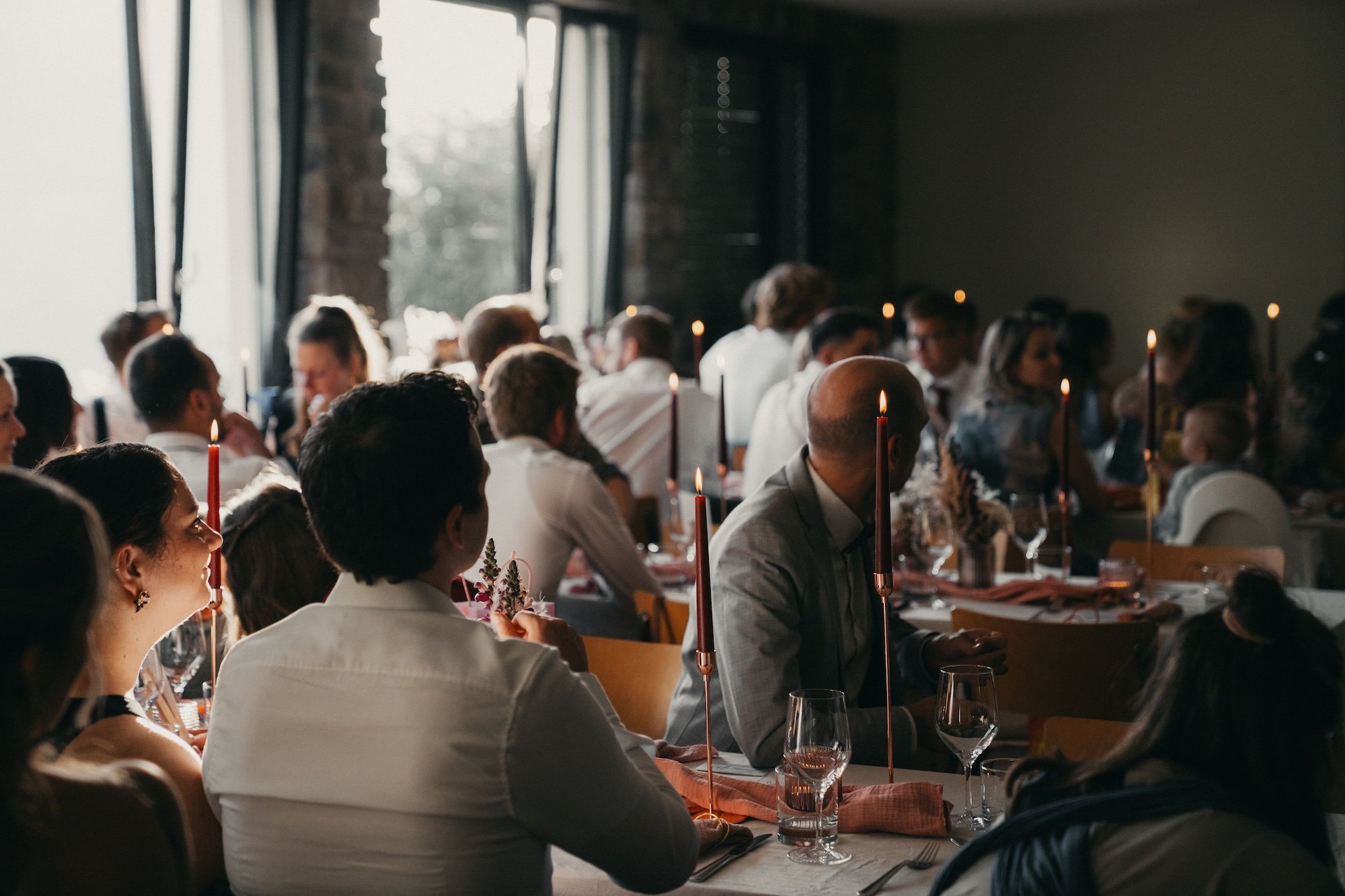 Hochzeitsgesellschaft beim Abendessen im warmen Kerzenlicht.