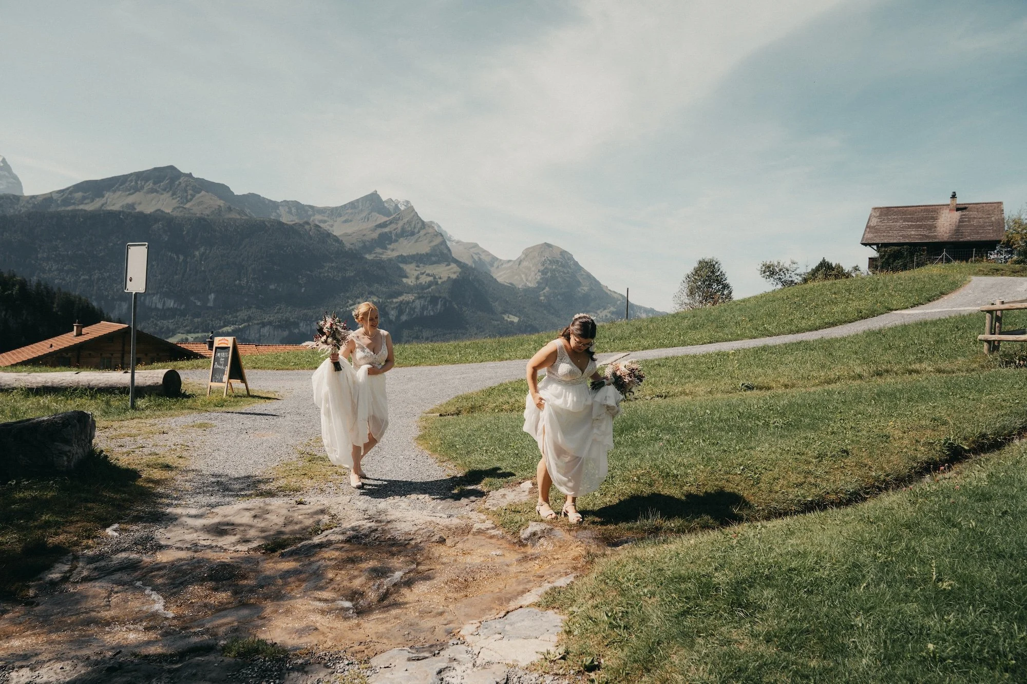Auf dem Weg zur Feier: Nadine und Svenja mit Brautsträussen vor der Bergkulisse.