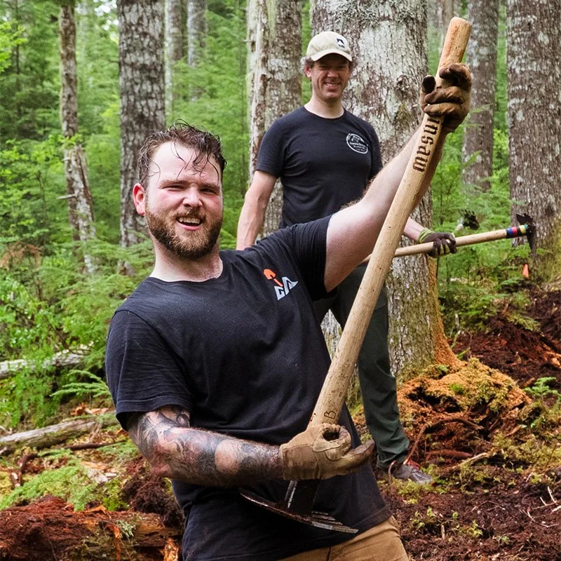Man playing air guitar while building mountain bike trail in Oregon