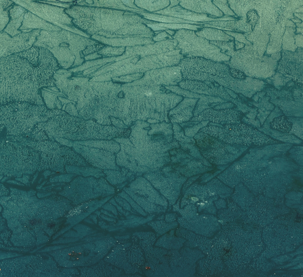 Aerial view of ice formations on a body of water with cracks and patterns.