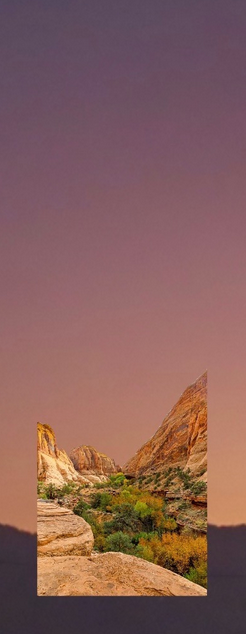 A cutout of a landscape with large rock formations and green vegetation under a gradient sky from purple to pink.