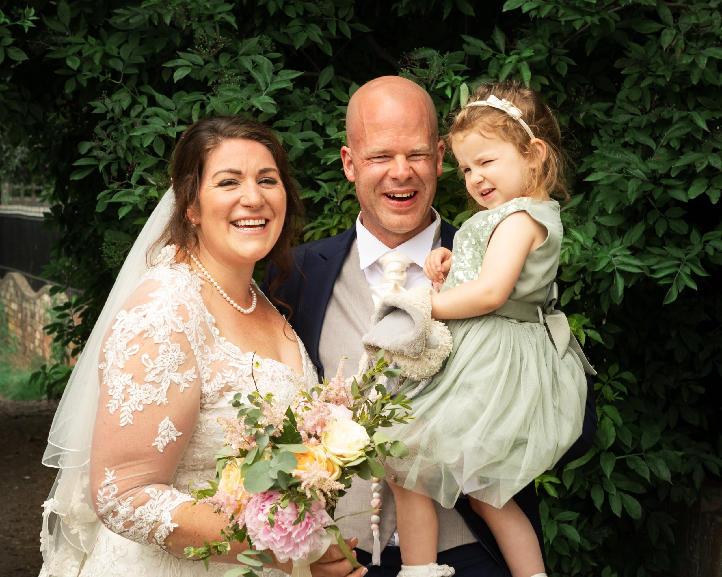 Bride-and-groom-holding-daughter-and-laughing.jpg