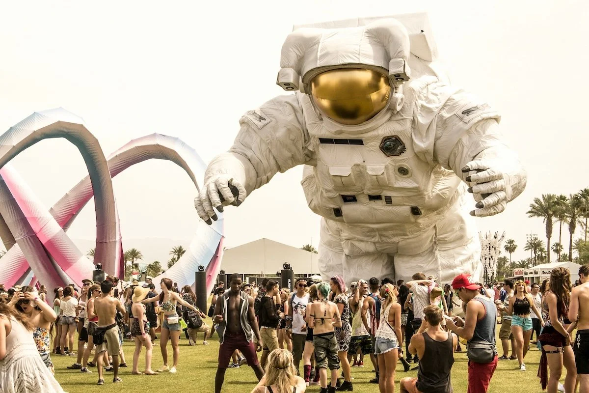Giant astronaut art installation "Overview Effect" towers over crowds at Coachella Valley Music and Arts Festival in Indio, California desert.