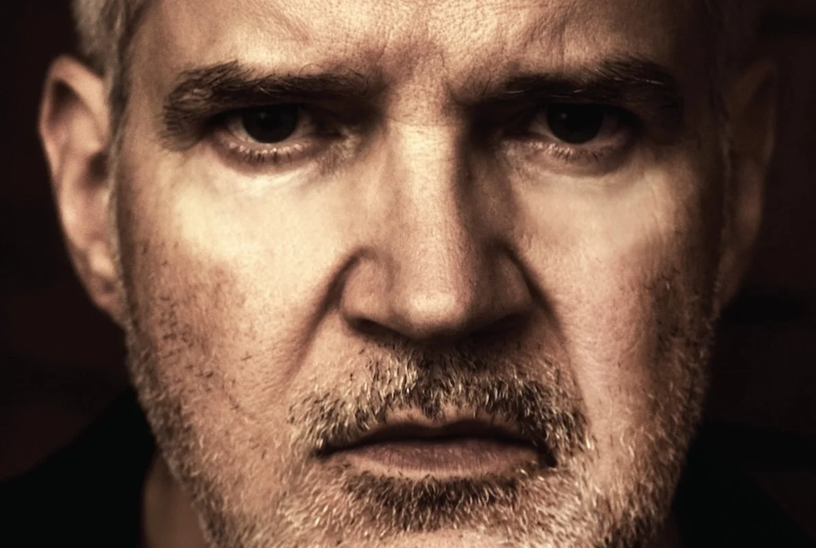 Close-up portrait of musician Lloyd Cole with a beard and intense expression.