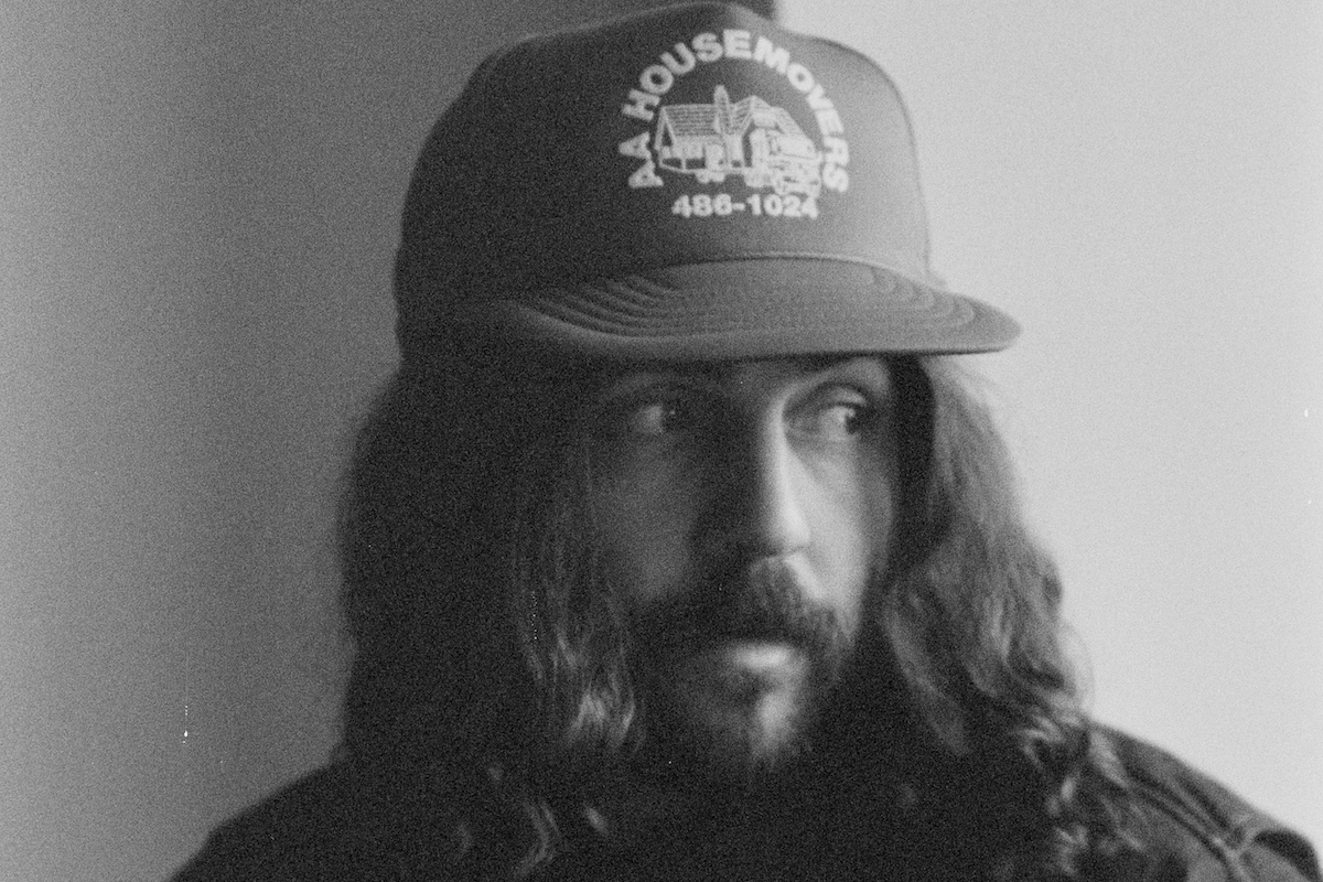 Hazlett portrait: Black and white photo of the Australian indie-folk singer-songwriter wearing a trucker hat and looking off-camera.