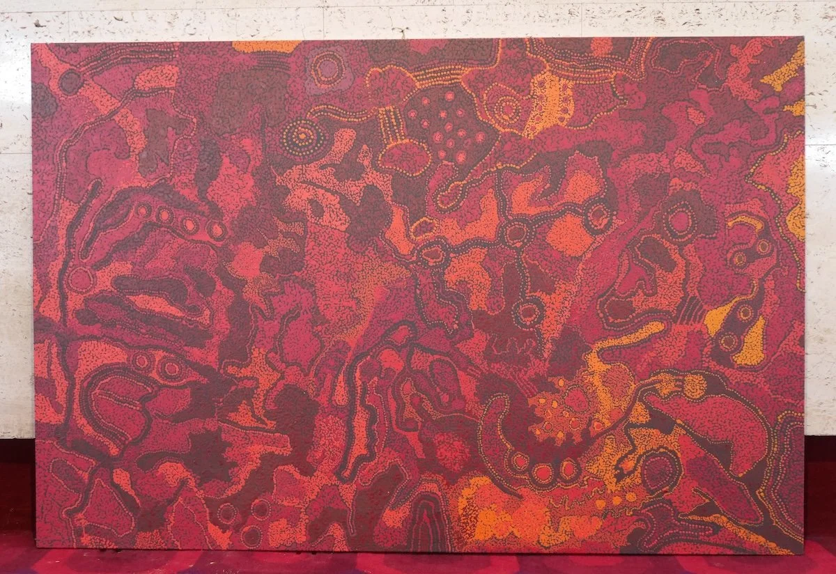 Aboriginal dot painting Malili Tjukurpa by Kani Patricia Tunkin (2014). Vibrant red, orange, and purple desert landscape patterns on canvas.