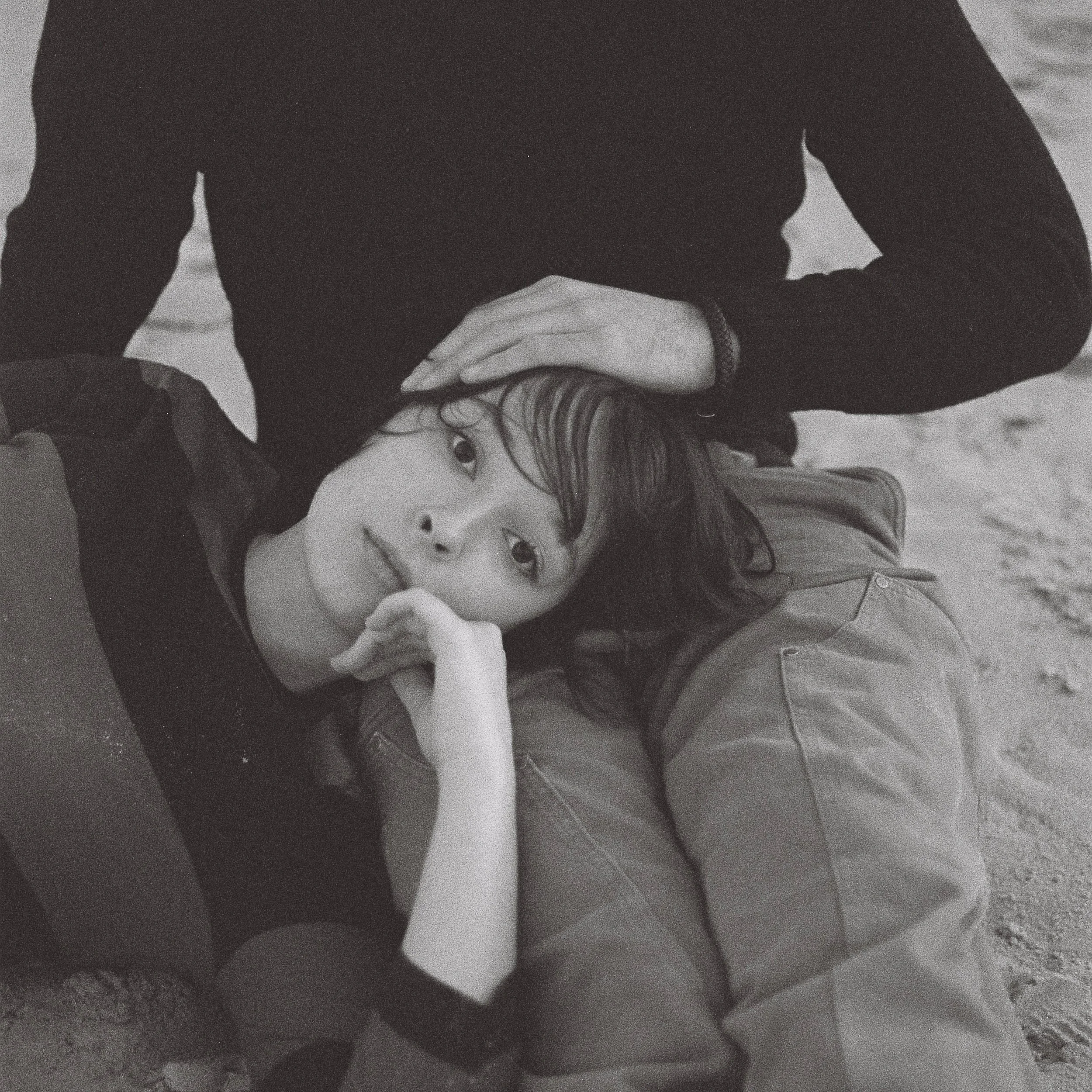 Lottie McLeod The Boat House EP cover: Black and white photo of a person resting their head on someone's lap on a sandy beach, looking upward.