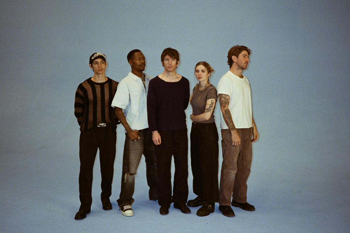 A promotional photo of the five members of the band Turnstile standing against a solid light blue background.