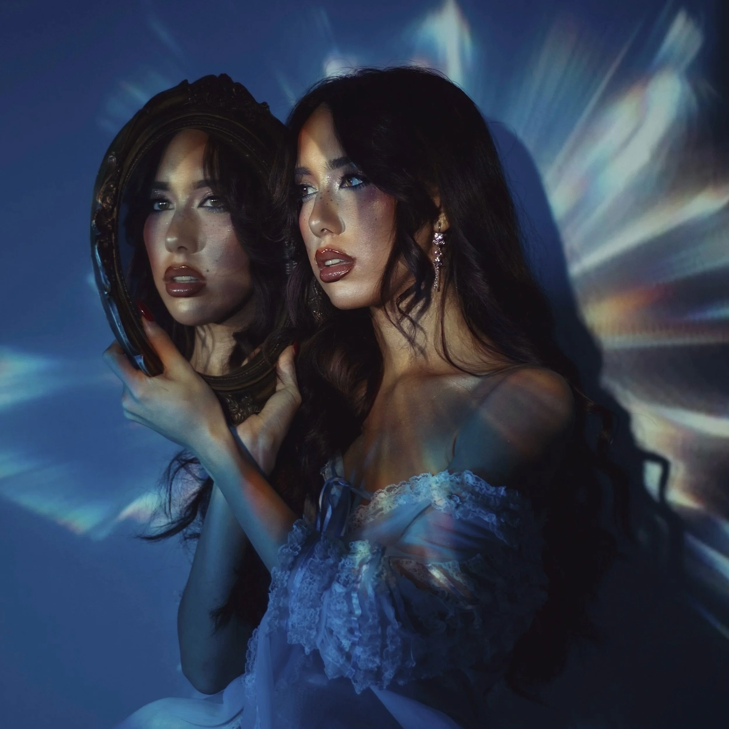 Liliana de la Rosa holds an ornate mirror reflecting her face in the 'Glass Skin' artwork, featuring ethereal blue lighting and prismatic light leaks.