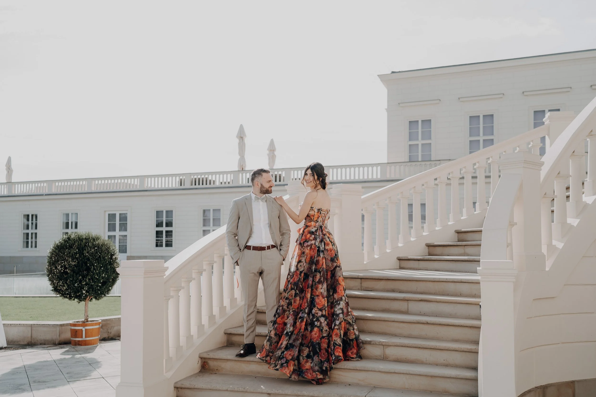 Ein verlobtes Paar steht auf der Treppe der Orangerie in Hannover den Herrenhäuser Gärten