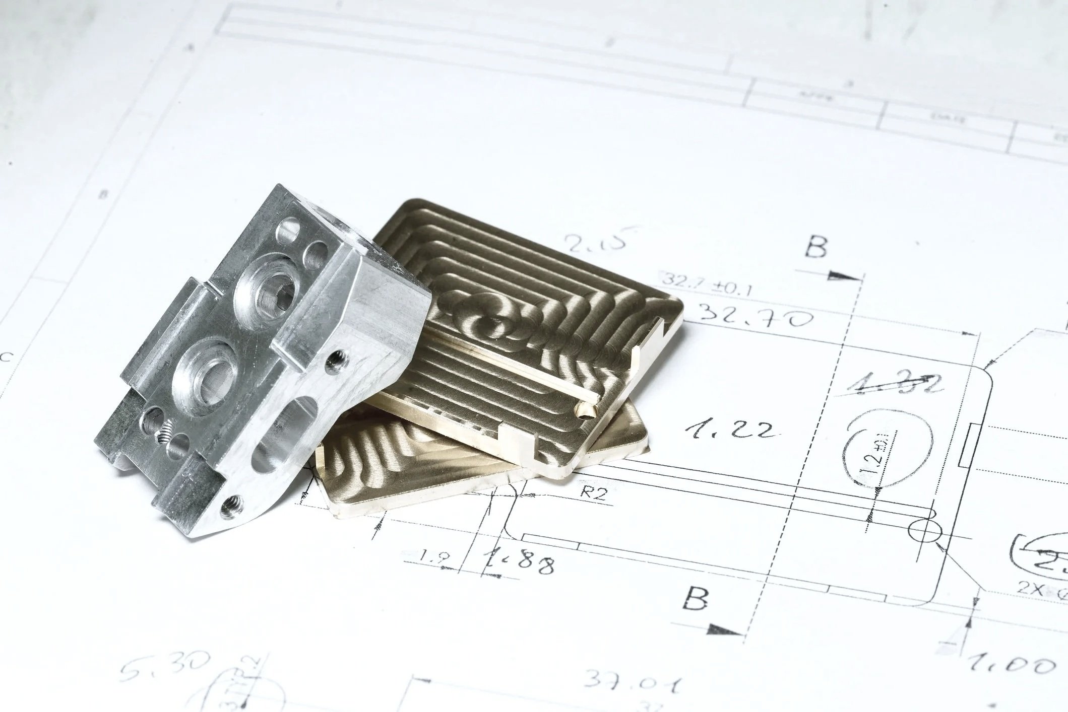 Pièces métalliques et plan technique d'ingénierie avec mesures et annotations.