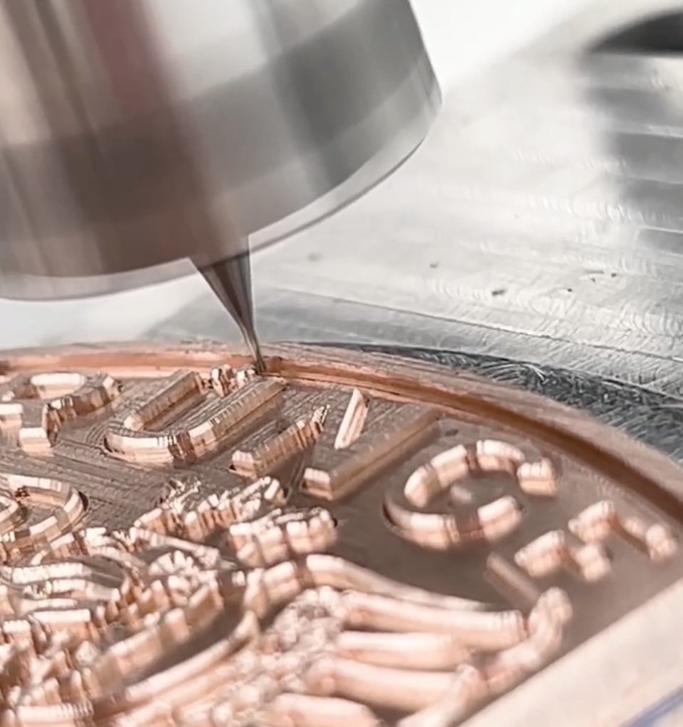 Une machine en train de graver un motif complexe sur une surface métallique.