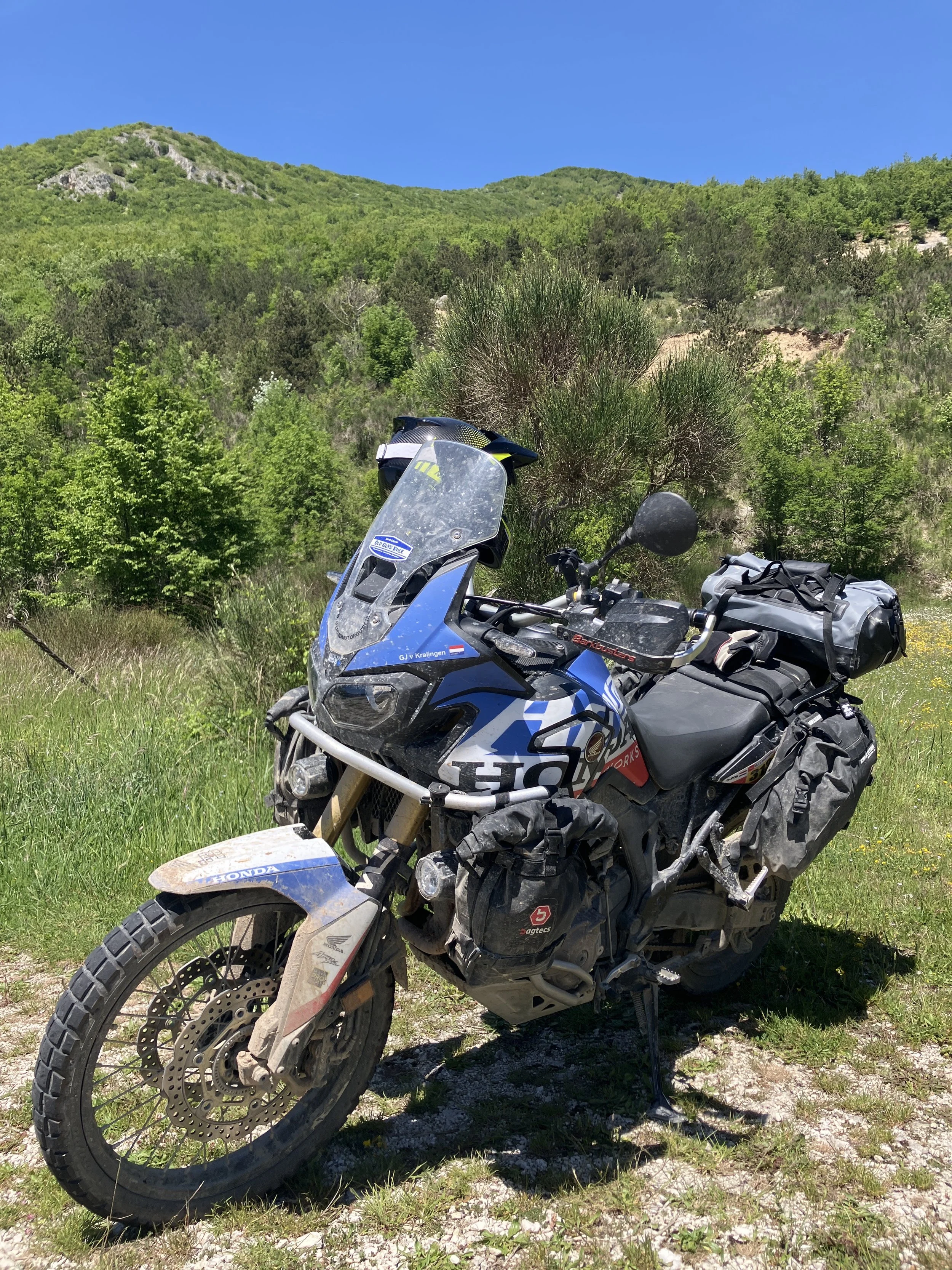 De allroad motor van Allroad Motor Guide in een natuurlijke omgeving met groene heuvels en een blauwe lucht tijdens een motorreis over de ACT Italy.