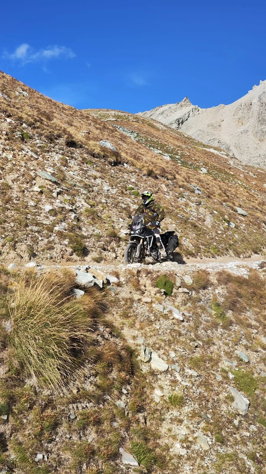 Allroad Motor Guide op een allroad motor op een bergachtig pad onder een heldere blauwe lucht.
