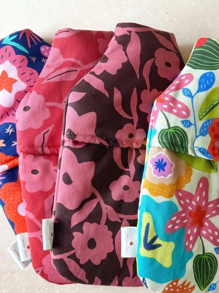 Four multicoloured floral patterned hot water bottle covers made in the UK by Jennie Fynn