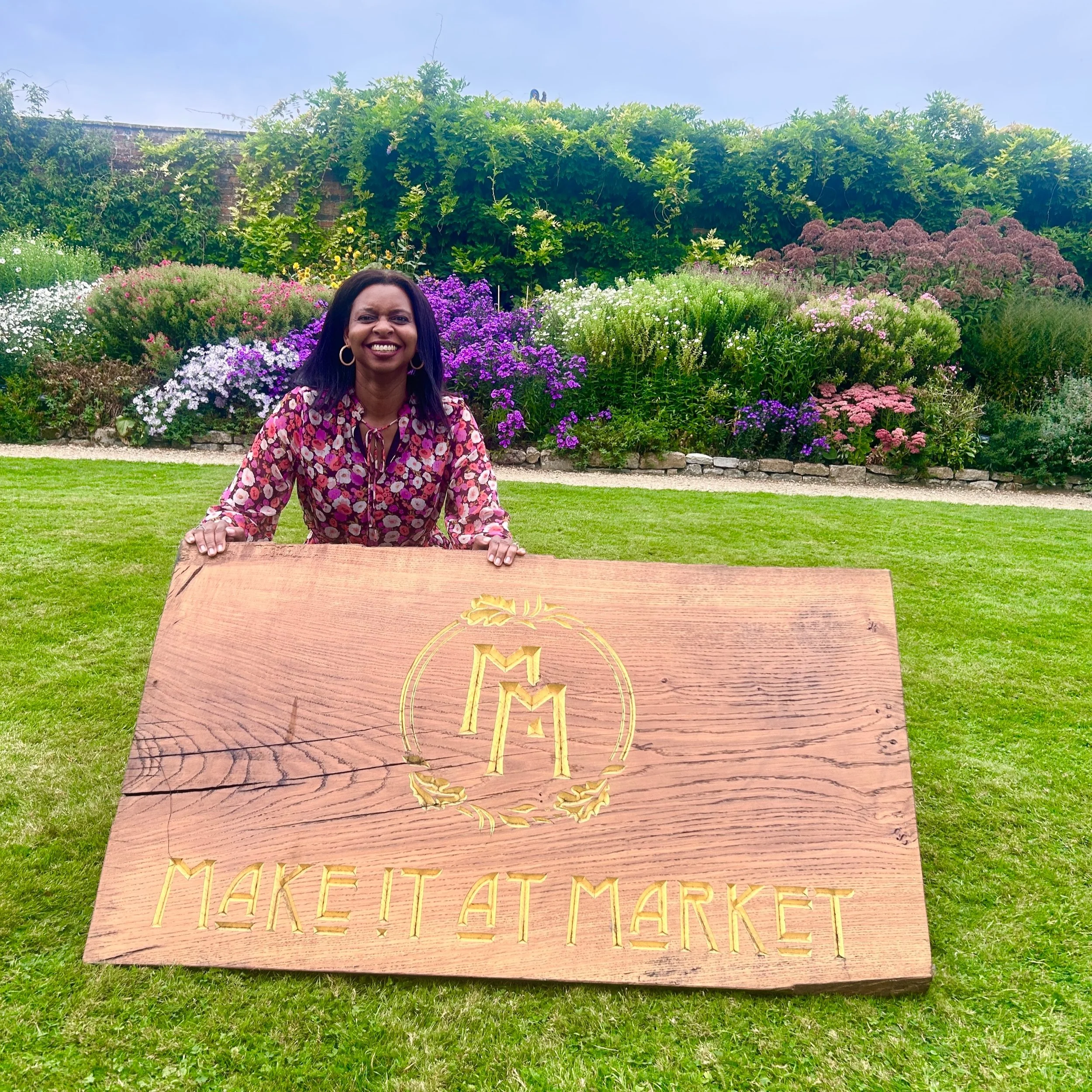 Fabric print designer Jennie Fynn standing behind the BBC One Make It At Market wooden and gold sign