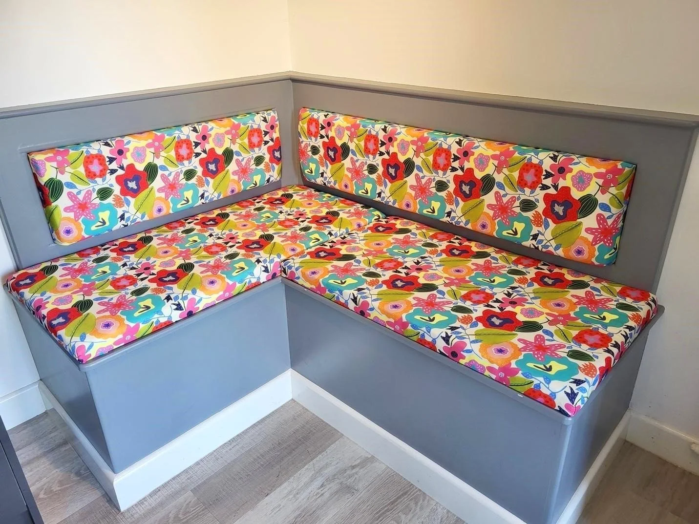 Large built in bench covered in bright multicoloured floral fabric for upholstery by Jennie Fynn