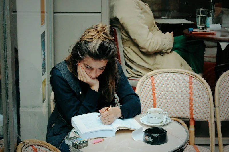 woman sits at cafe with head in hand