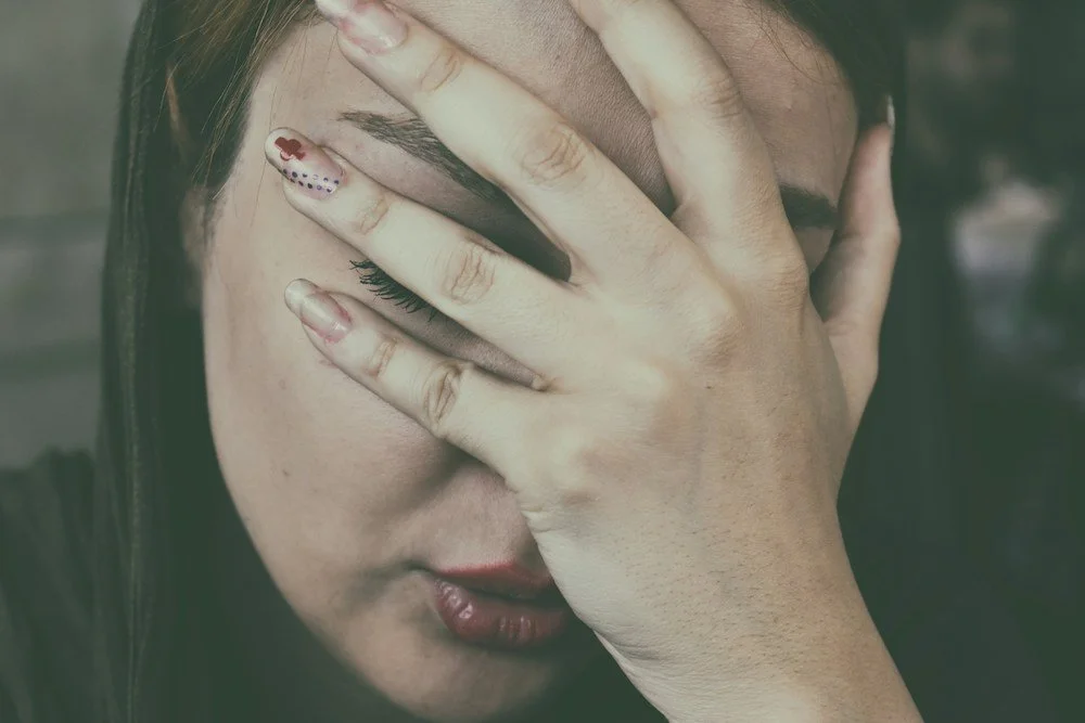 woman puts hand over face