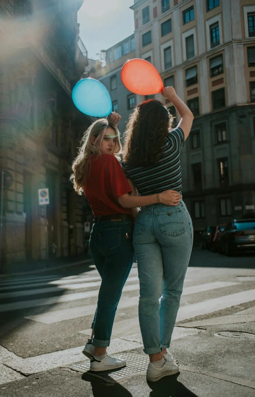 two women holding balloons, one looking back at camera