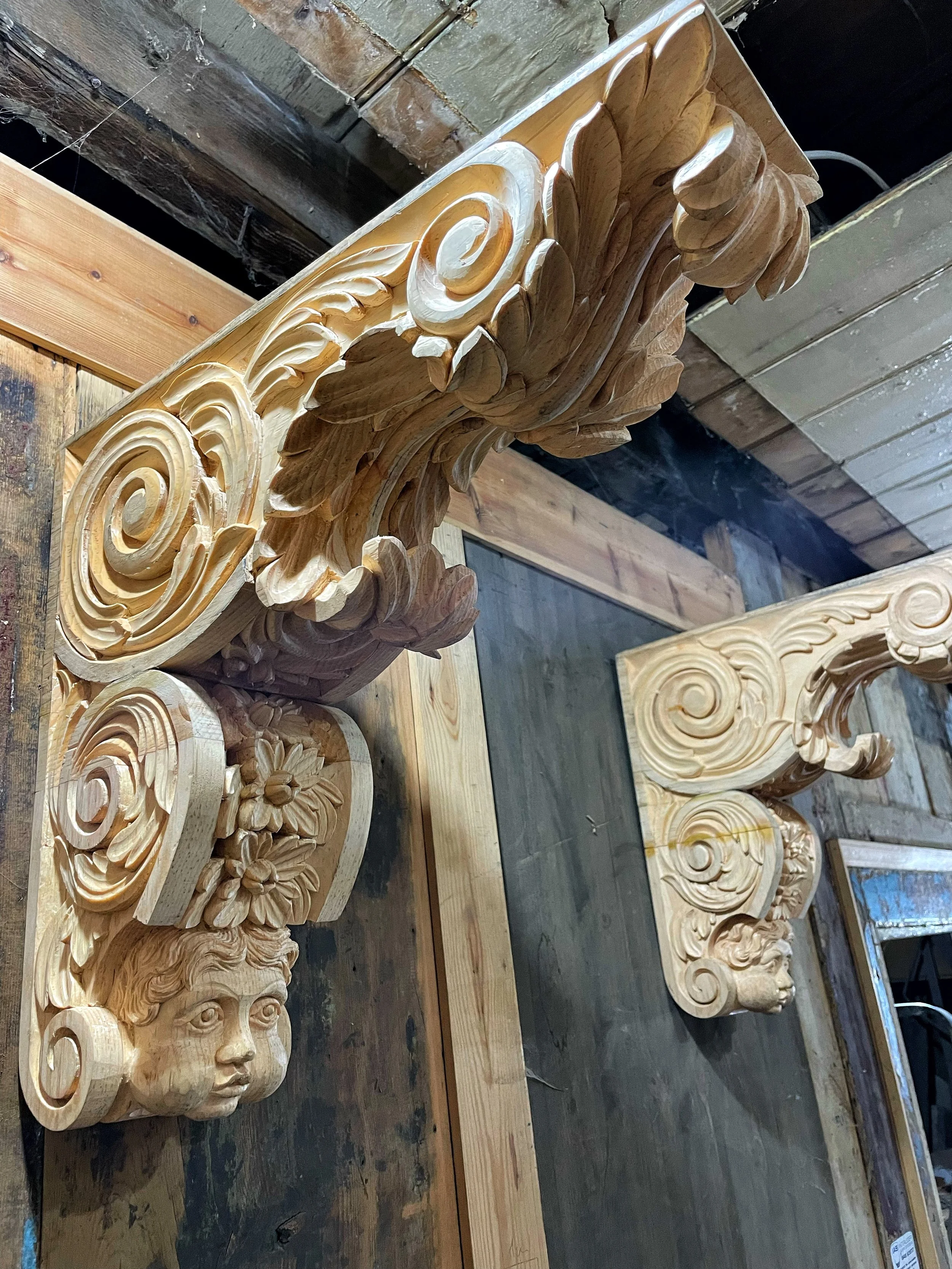 Wooden carved architectural corbel with a face, floral motifs, and swirling designs.