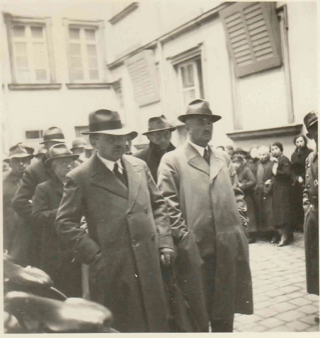 Heinrich Brill, Laura W. Brill’s great grandfather, walking between two men during a public roundup of Jewish residents, surrounded by a crowd.
