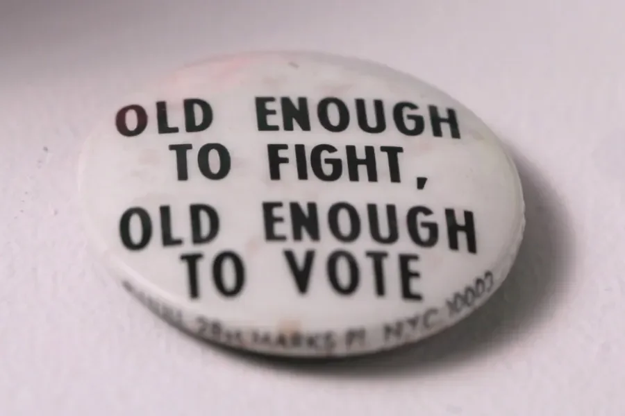 Button reading “Old enough to fight, old enough to vote,” a slogan associated with the 26th Amendment.