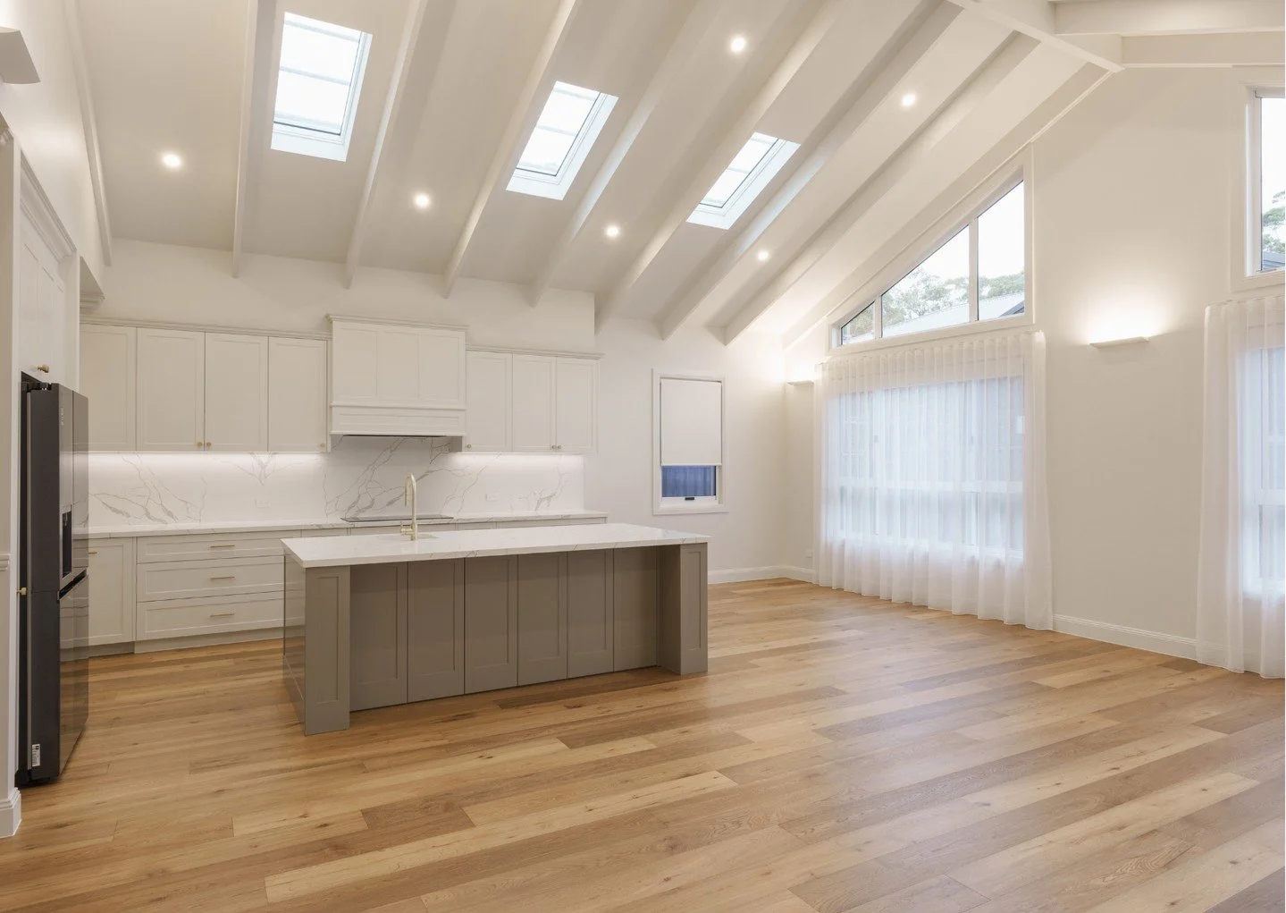 We're still over the moon about this living space.⁠
⁠
A soaring cathedral ceiling and expansive windows flood the home with natural light, creating a bright, airy feel throughout. The open-plan design seamlessly connects the kitchen and living areas,
