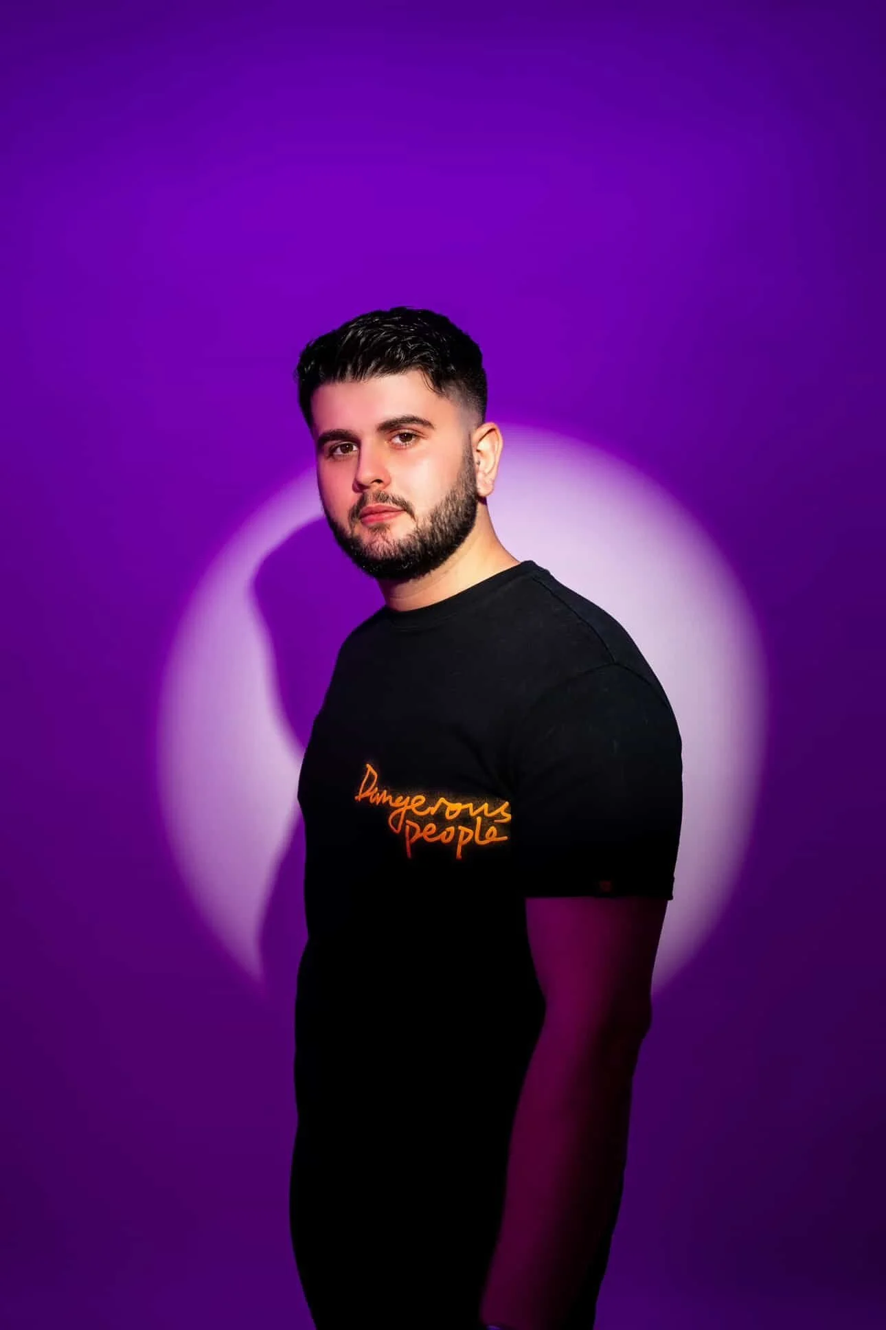 DJ Korvaia with dark hair and a beard, wearing a black T-shirt