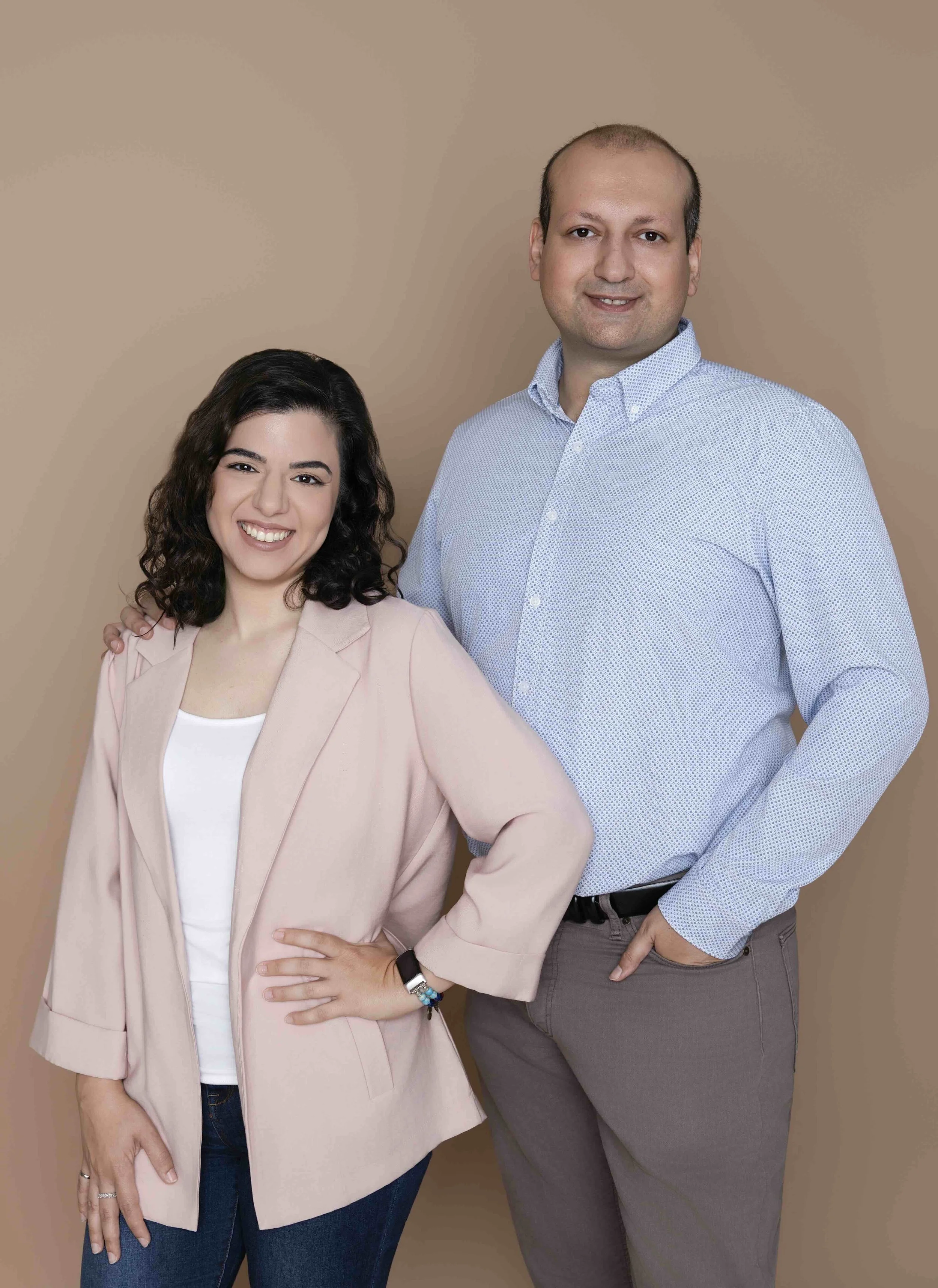 A professional portrait of wedding planners Bahar and Hamed dressed in elegant formal attire against a neutral backdrop.