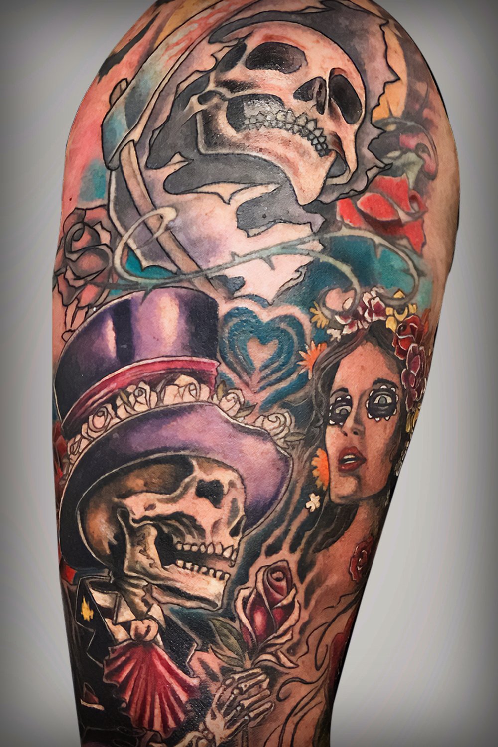 Day of the dead themed tattoo featuring a skeleton in a top hat, and a beautiful woman dressed as la Catrina.