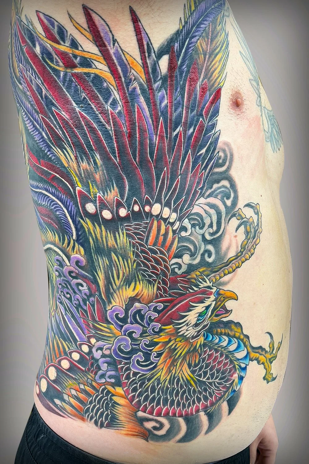 A tattoo spanning the entire rib cage, from just beneath the armpit to the hip bone, slightly wrapping toward the chest and back. 