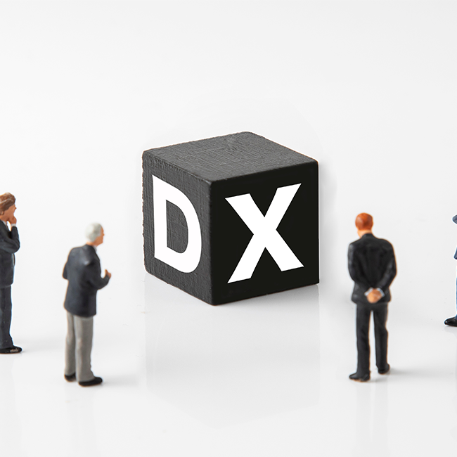 Miniature businesspeople gathered around a black cube with the letters D and X on its sides, on a white background.