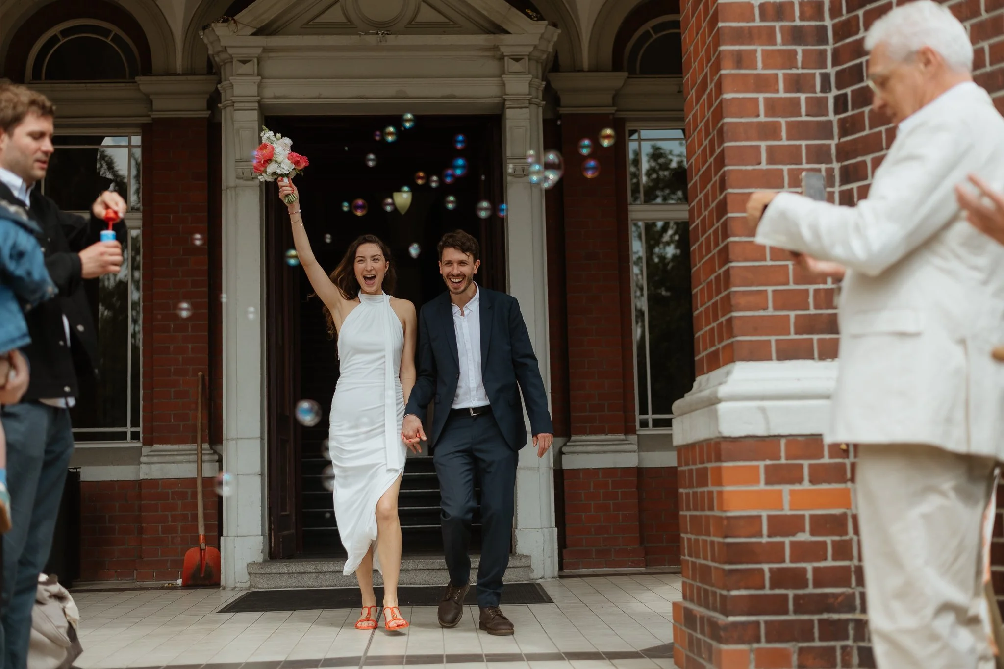 Lachendes Paar läuft an Hochzeitslocation, Seifenblasen in der Luft – Hochzeitsreportage Berlin