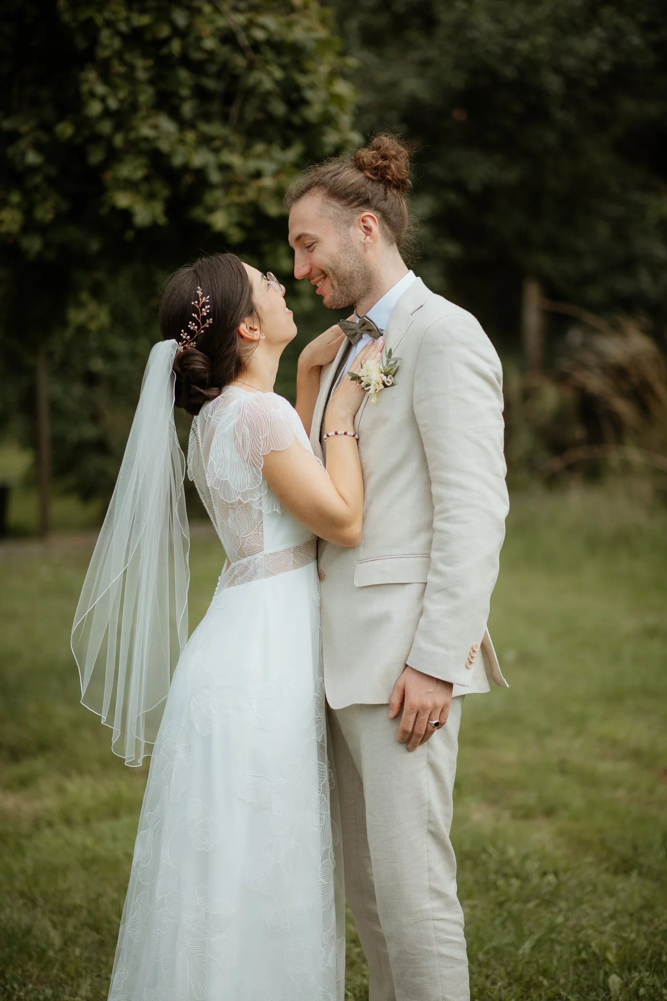 Ein Brautpaar steht draußen im Park und schaut sich verliebt an.