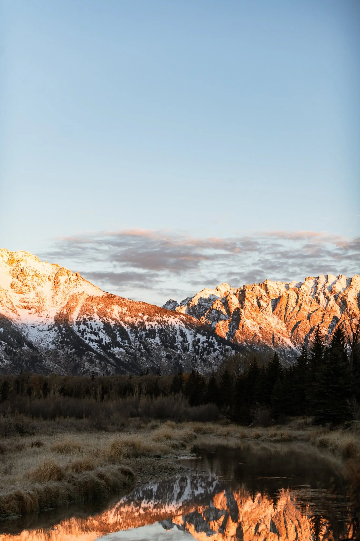 Berglandschaft mit schneebedeckten Gipfeln, reflektiert im Wasser, bei Sonnenuntergang in den Bergen.