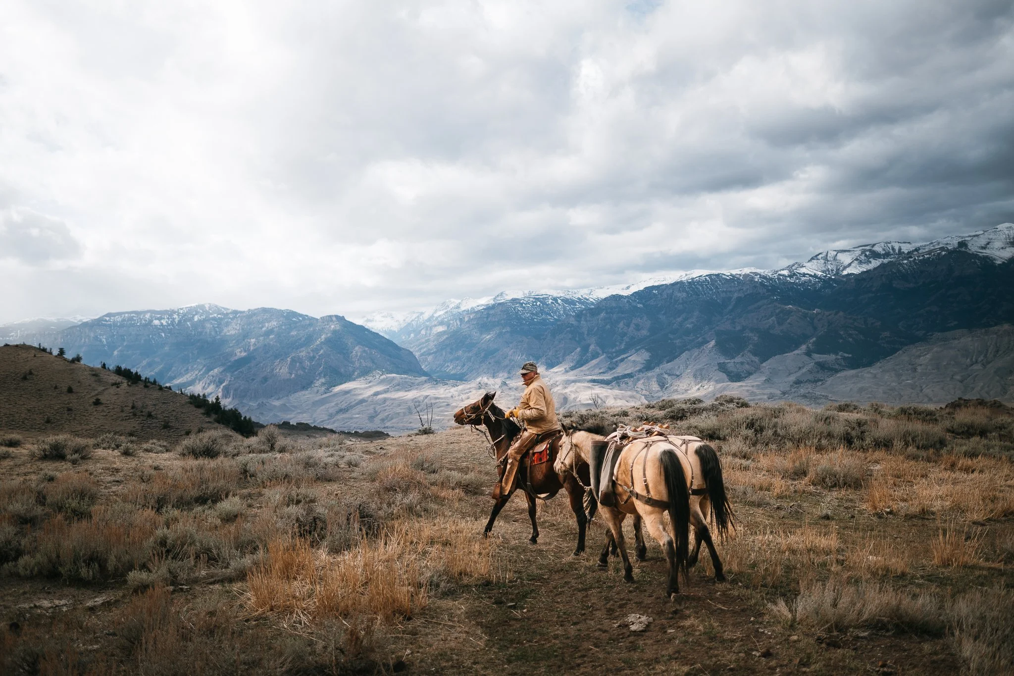 Mann reitet auf Pferd durch bergige Landschaft – Reisefotografie USA Wyoming
