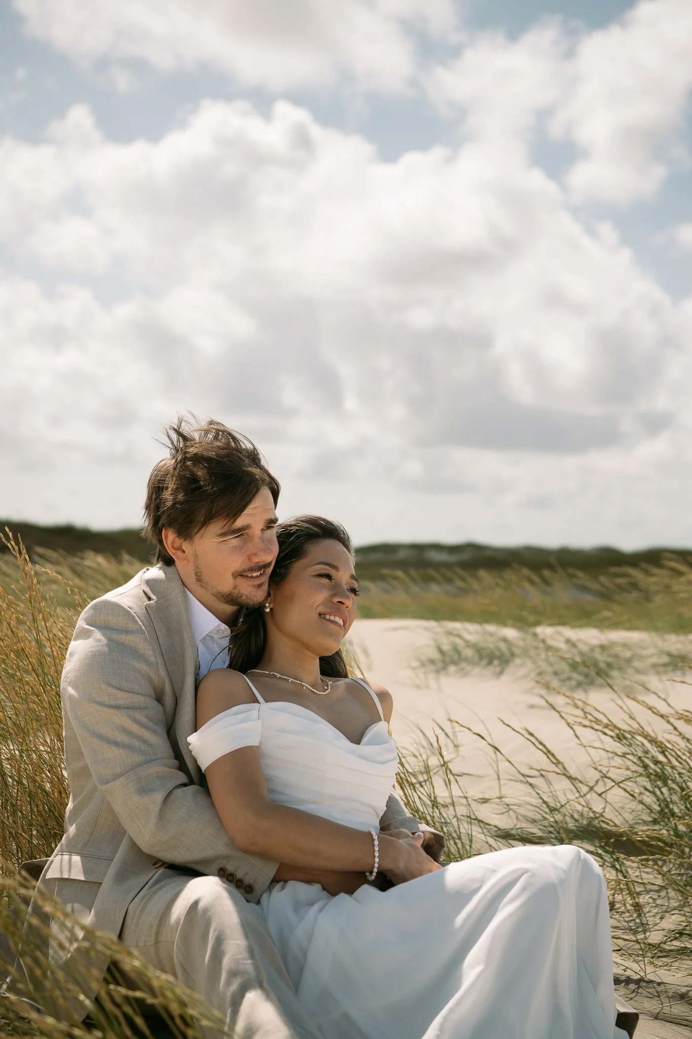 Brautaar sitzt am Sandstrand, umgeben von Gräsern – Hochzeitsreportage Berlin & Brandenburg