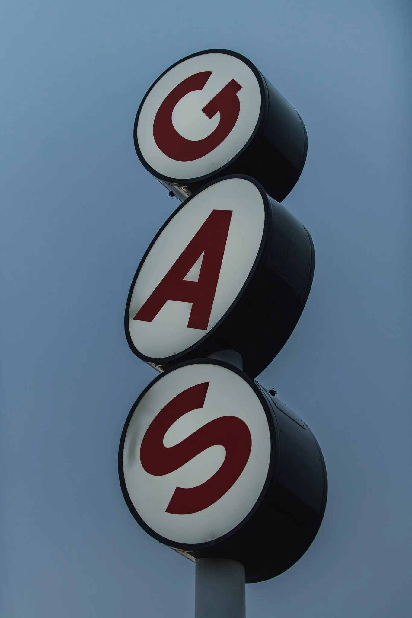 Ein an einer Stange befestigtes Verkehrszeichen mit den Buchstaben G, A und S in rot auf weißen Kreisflächen, gegen den blauen Himmel.