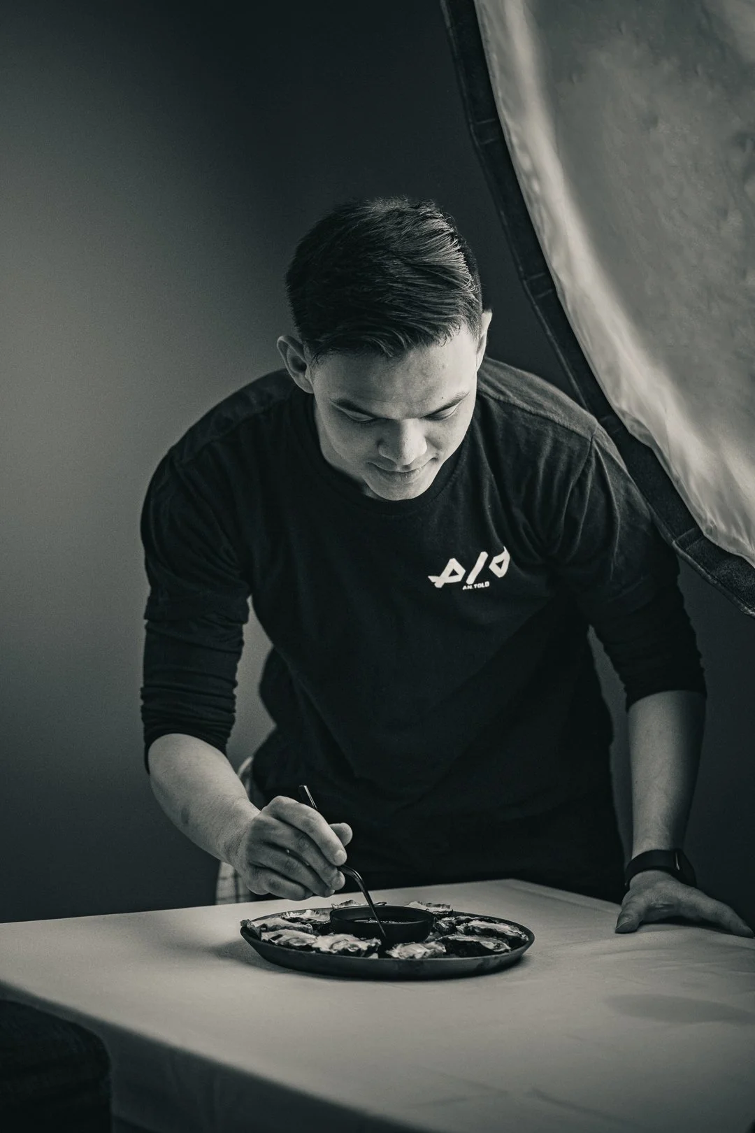 Person plating food at a table with a softbox lighting equipment nearby.