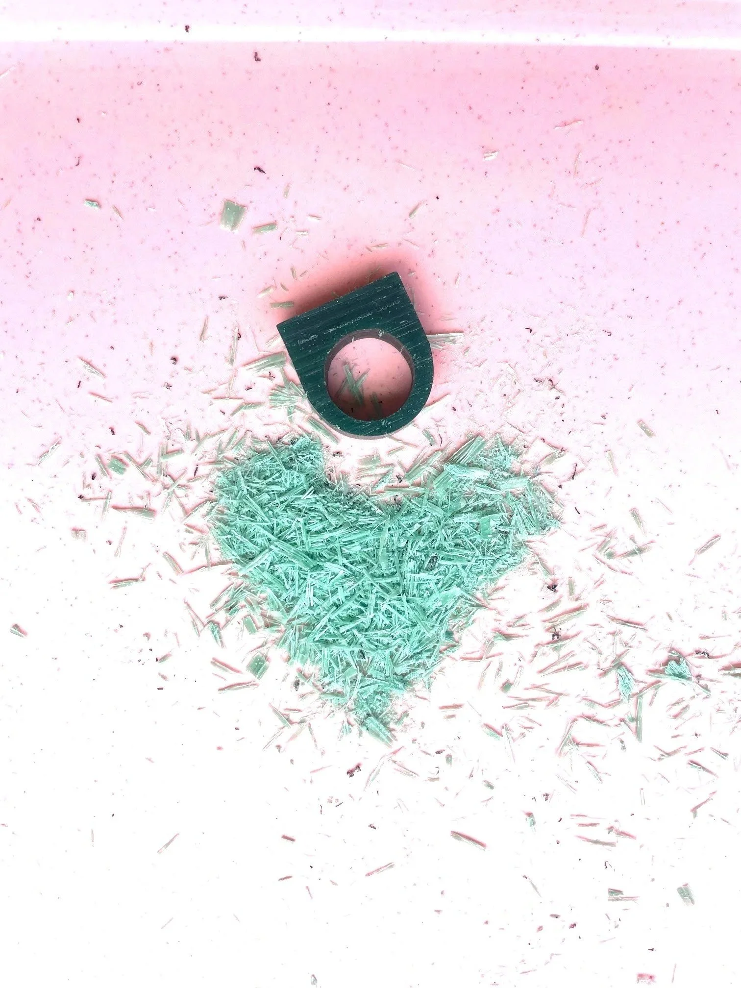 wachsring liegt auf rosa tablett und wachsspäne in grün die die form von einem herz bilden