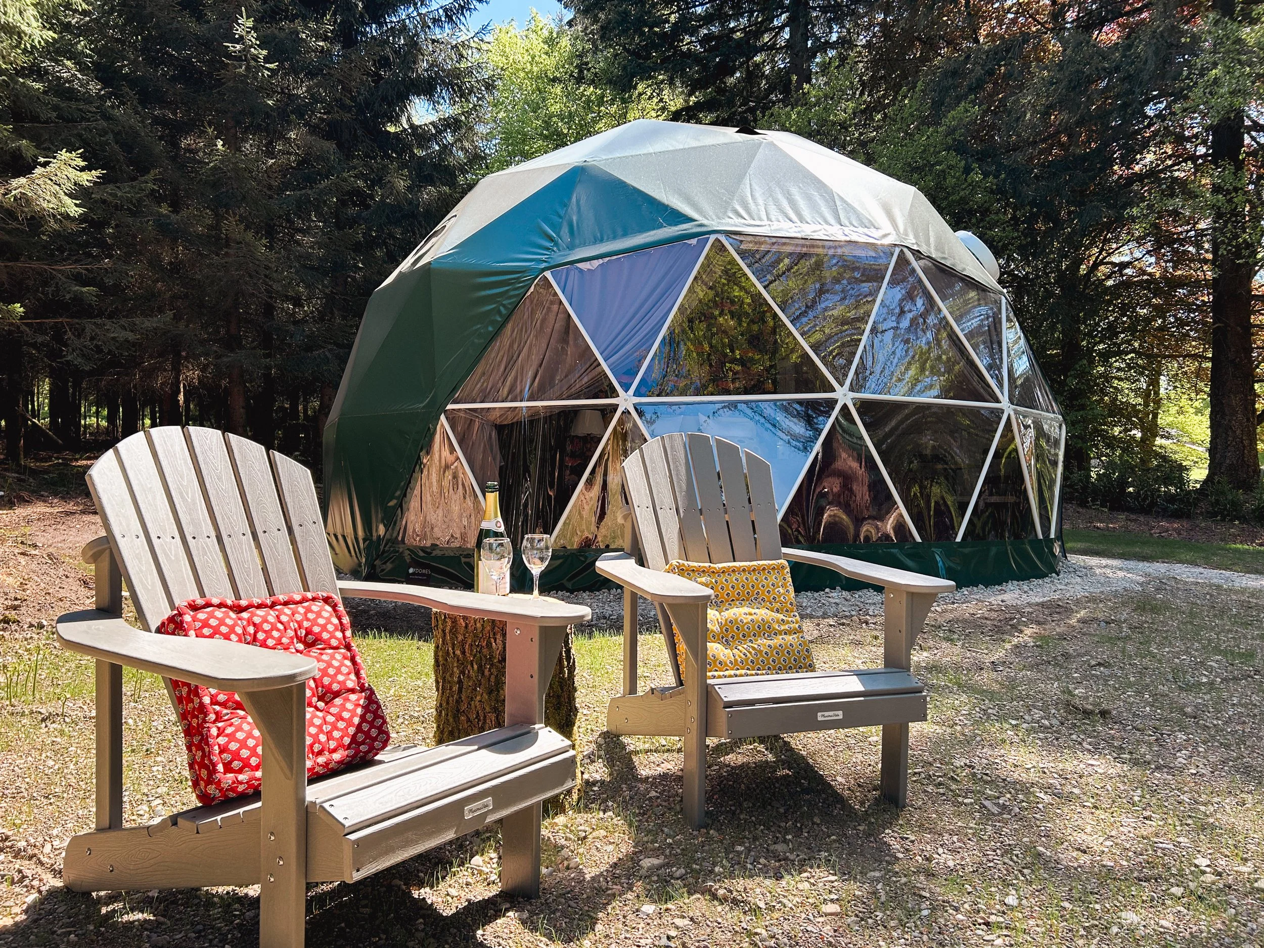 Relaxing outdoor seating area with two Adirondack chairs beside the glamping dome