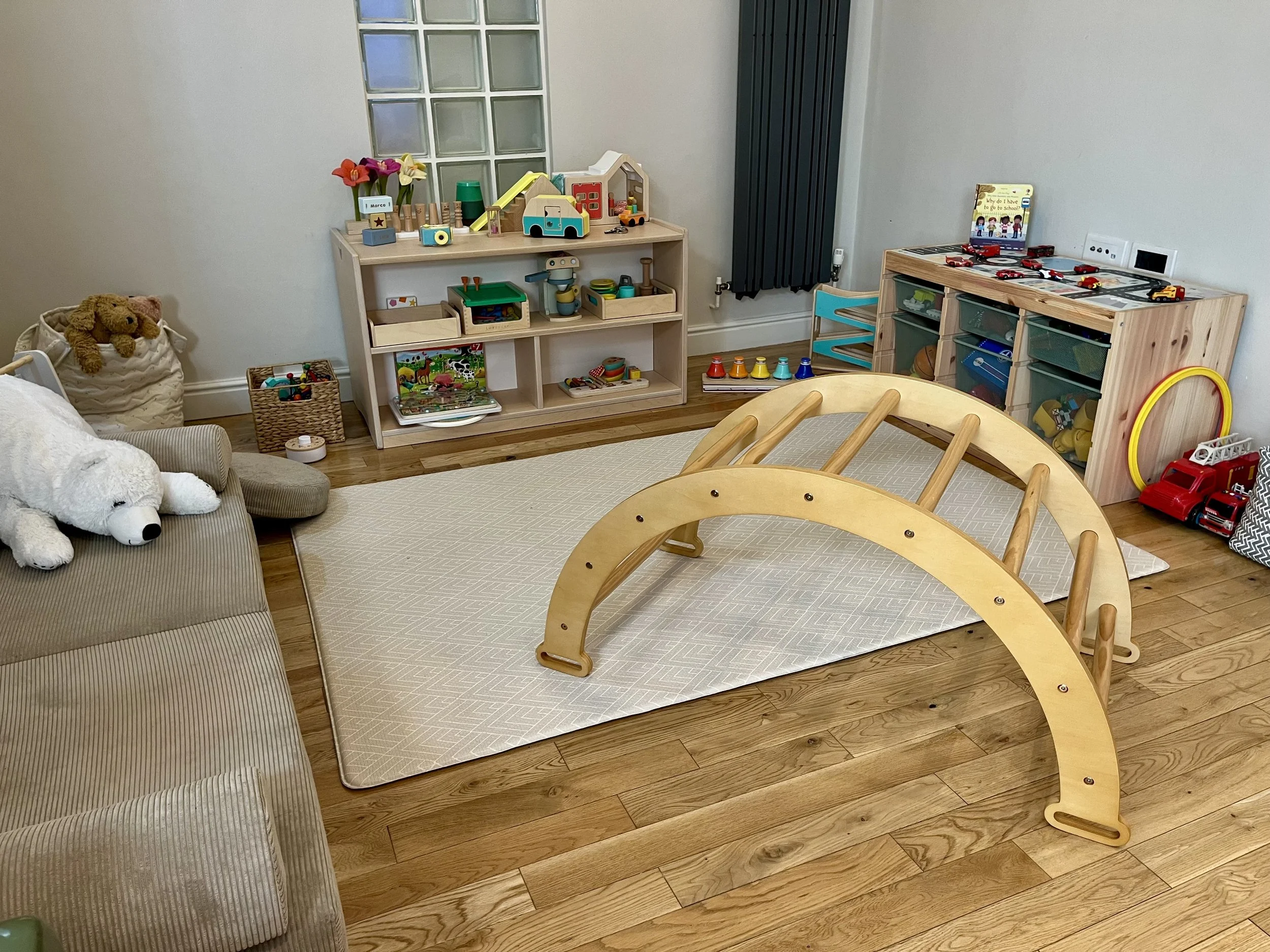 Calm, thoughtfully organised playroom with clearly defined play areas and accessible toys, designed to encourage children's independence, focus and meaningful play.
