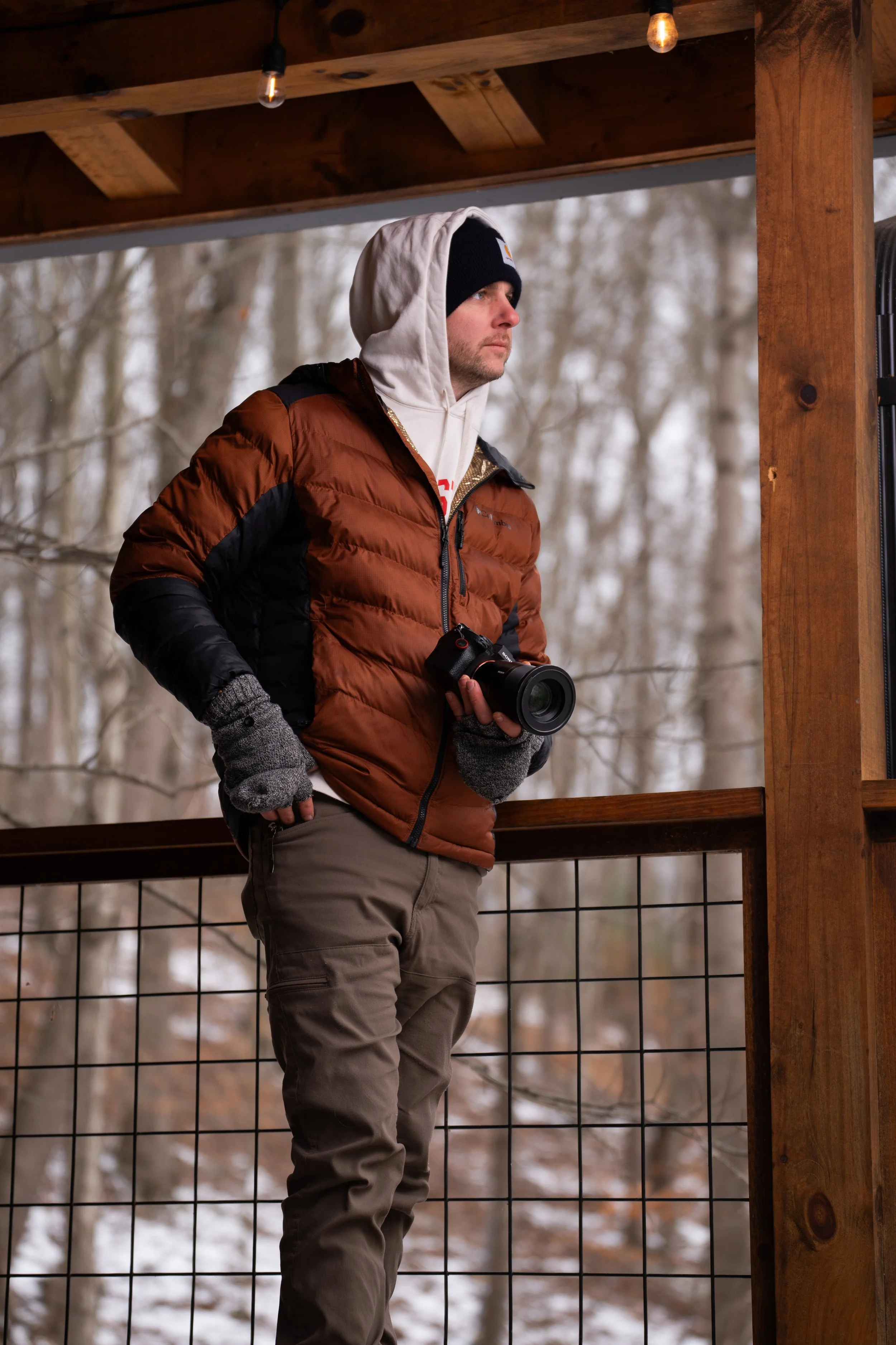 Man holding camera on a deck during the winter.