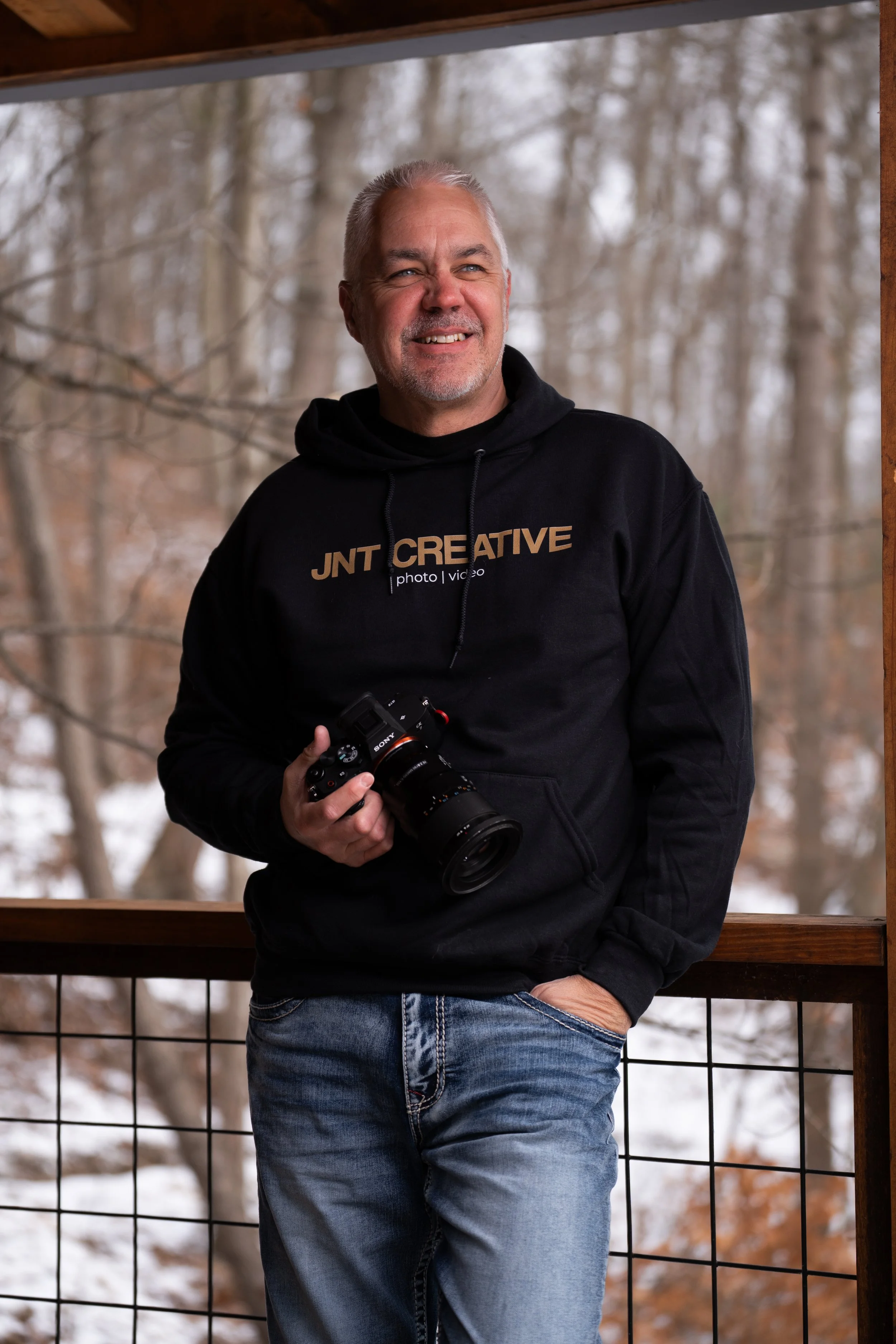 Man holding camera on a deck during the winter.
