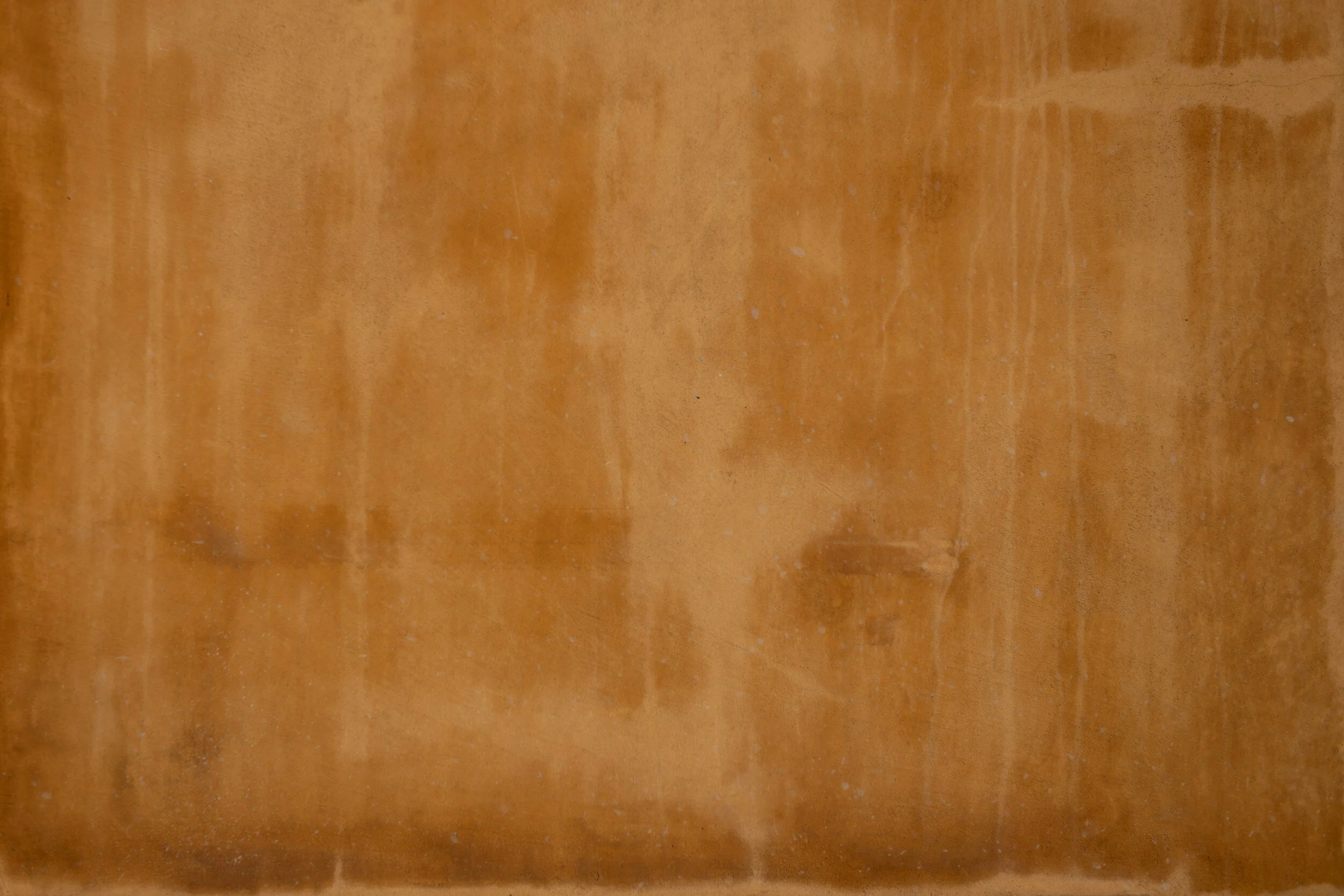 Close-up of a wooden surface with a warm, orange-brown hue, showing natural grain and texture.