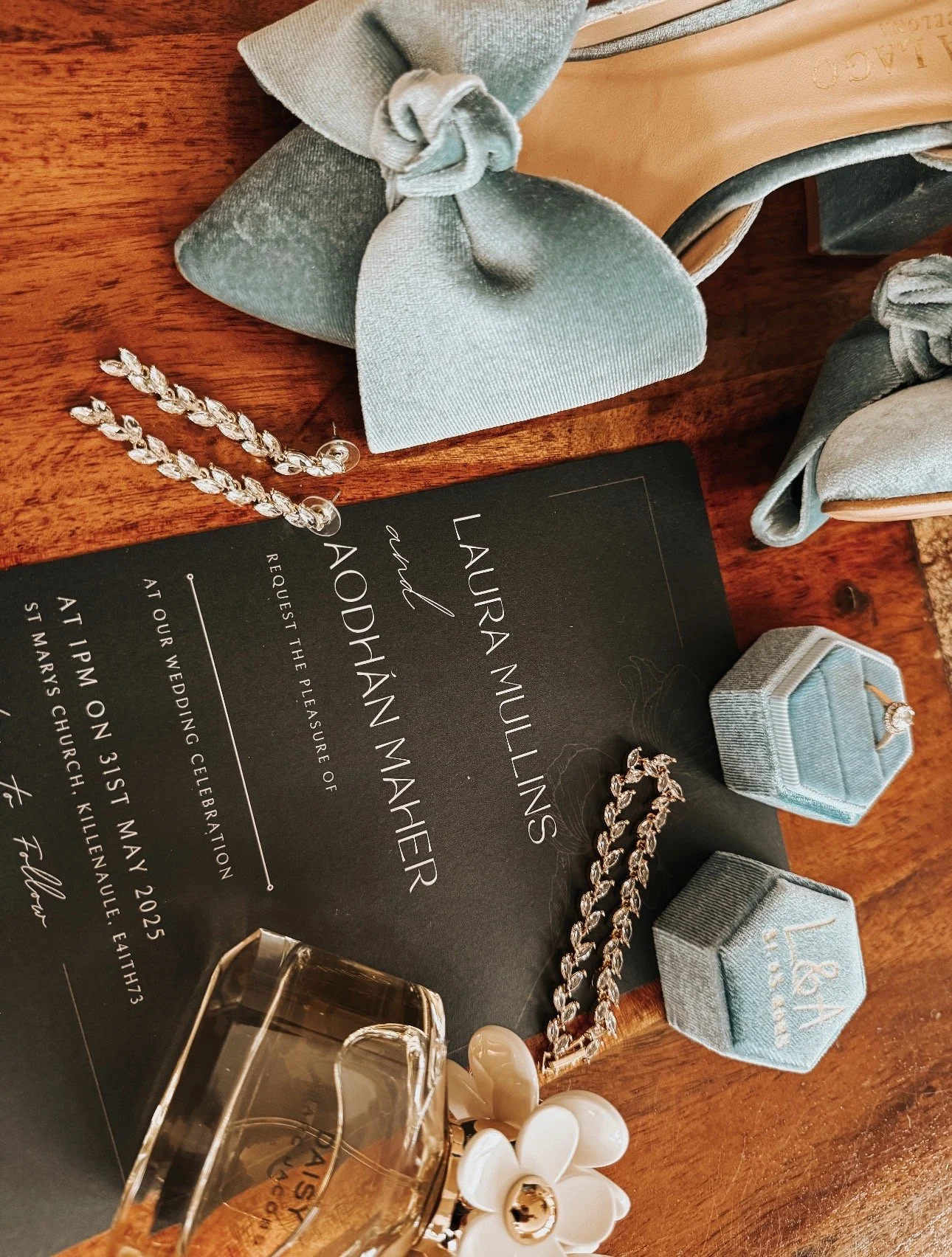 Wedding Flat lay captured by Wedding Content Creator Ireland. Grey Acre Studios, with an Invitation card for a wedding with jewelry, shoes, and perfume accessories on a wooden surface.