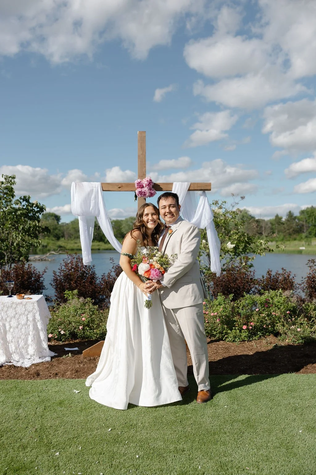 A black-and-white photo of a bride and groom holding hands behind a wooden partition, with the bride wearing a lace wedding dress.